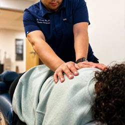 Practitioner applying pressure to a patient lying face down on a treatment table during care.