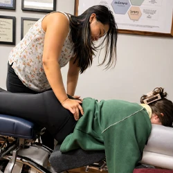 Practitioner performing a chiropractic adjustment on a patient lying face down on a treatment table.