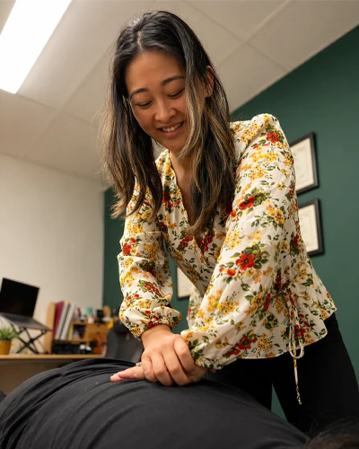 Dr. Eva Quach during a chiropractic adjustment on a patient lying face down on a treatment table.